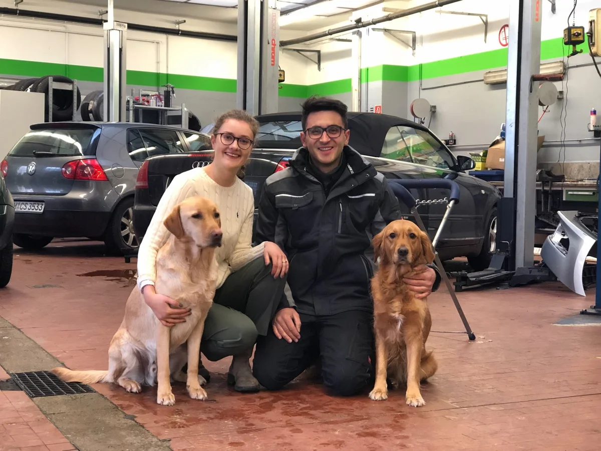 Das Team des KFZ Meisterbetrieb Schwabing mit Familie und Hunden vor der Werkstatt